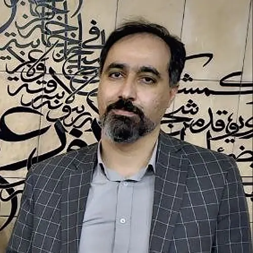 پرتره دکتر رضوی‌فرد در مقابل پس‌زمینه خوشنویسی ایرانی، با پوشش رسمی و نگاه مستقیم به دوربین.